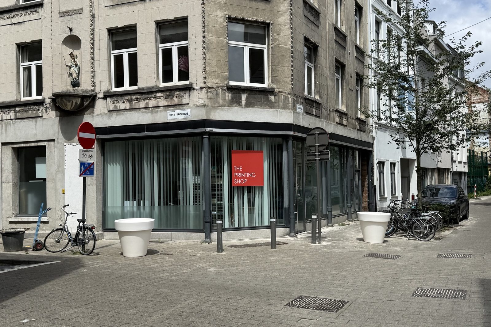 The Printing Shop on a street corner, with the red logo in the window